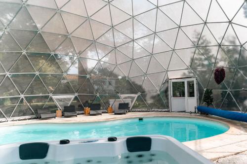 una piscina con una piramide di vetro simile a un edificio di Mas du Versadou, dans un espace naturel protégé, piscine Chauffée, Spa et salle de jeux a Saint-Gilles