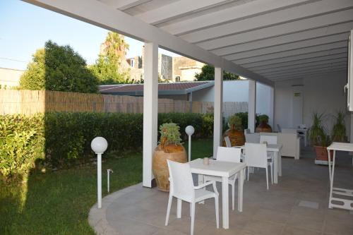 un patio con mesas blancas y sillas en el césped en Il Matino, en Leverano
