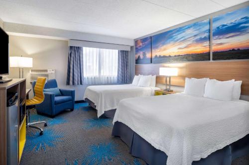 a hotel room with two beds and a television at Days Inn by Wyndham Sioux Falls Airport in Sioux Falls