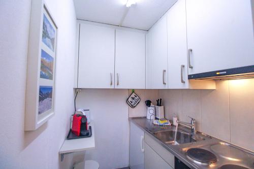 a kitchen with white cabinets and a sink at Studio Wolli - Stylish & Central - steps to Matterhorn gondola in Zermatt