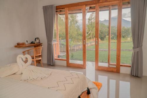 a bedroom with a bed and a large window at Hillside bali in Kubupenlokan