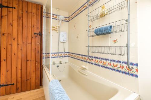 a bathroom with a tub and a wooden door at Dairy Cottage in Roffey