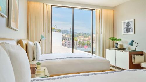 a bedroom with two beds and a large window at Thompson Hollywood, part of Hyatt in Los Angeles