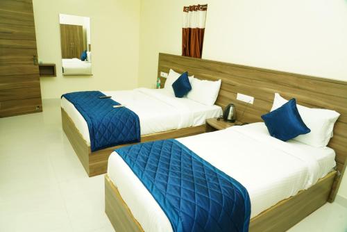 two beds in a hotel room with blue and white at NJK Residency in Yercaud
