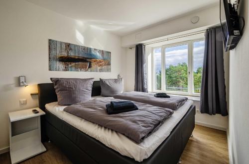 ein großes Bett in einem Zimmer mit einem großen Fenster in der Unterkunft FeWo Prora - See(h)nsucht in Binz