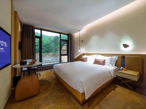 a bedroom with a large bed and a large window at Novotel Linfen Mount Yun in Xiangning
