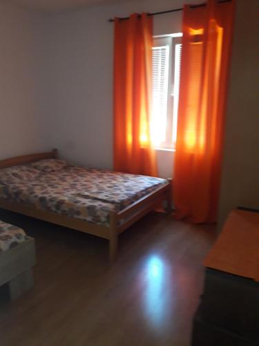 um quarto com uma cama e uma janela com cortinas laranja em Mir em Kotor