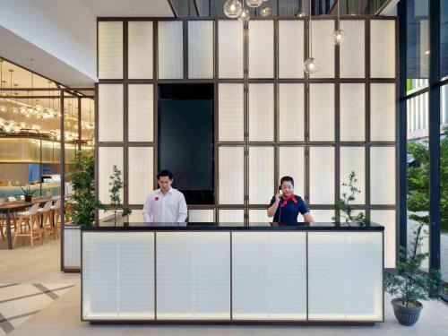 two men standing behind a counter in a building at ibis Palembang Sanggar in Palembang