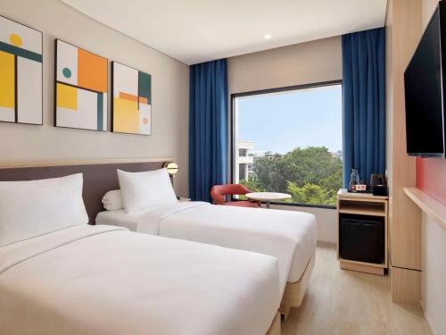 a hotel room with two beds and a window at ibis Palembang Sanggar in Palembang