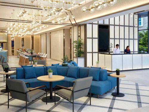 a lobby with blue couches and tables and a tv at ibis Palembang Sanggar in Palembang