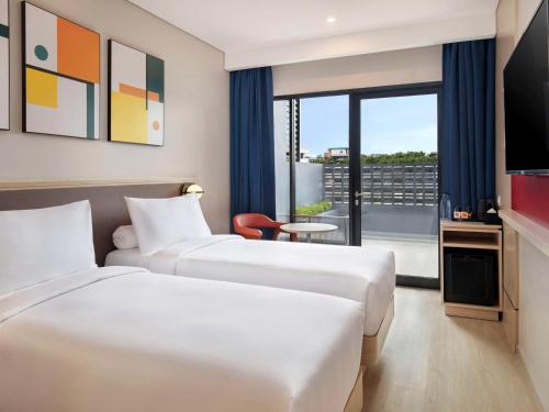 two beds in a hotel room with a balcony at ibis Palembang Sanggar in Palembang