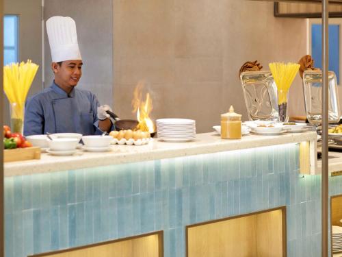 a chef is preparing food in a kitchen at ibis Palembang Sanggar in Palembang
