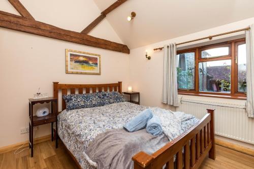 a bedroom with a bed and a window at Dairy Cottage in Roffey