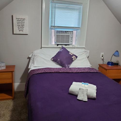 ein Schlafzimmer mit einem lila Bett mit zwei Handtüchern darauf in der Unterkunft Bungalow by the Beach in Hampton