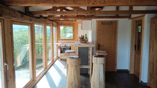 a kitchen with wooden walls and windows and wooden stools at Ferienhaus am Bückeberg in Gernrode - Harz
