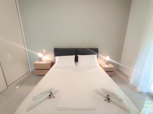 una camera con un letto bianco con due lampade sui tavoli di Casa Elegante a Potamós