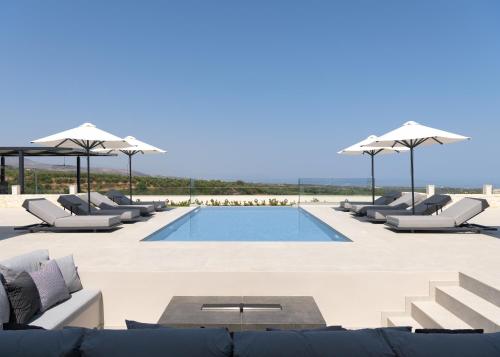 a swimming pool with lounge chairs and umbrellas at Caelum Villa, By Hellocrete in Píkris