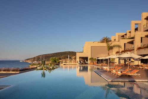 a large swimming pool with chairs and a hotel at Caresse, a Luxury Collection Resort & Spa, Bodrum in Bitez