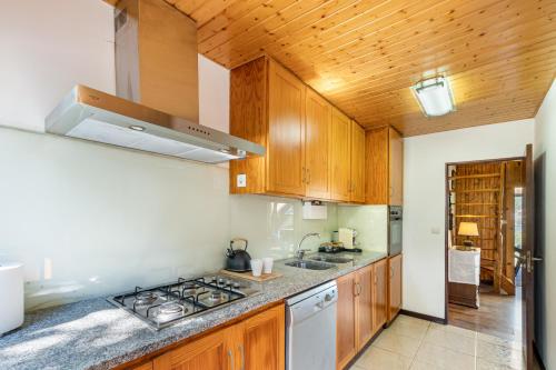 a kitchen with wooden cabinets and a stove top oven at Chalé da Caniçada By Sé Apartamentos in Rio Caldo