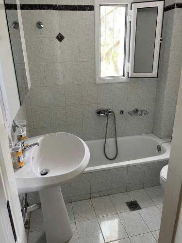 un bagno con lavandino e vasca da bagno di BEACH HOUSE SEAFRONT VILLA LATOURA ORMOS PANAGIAS a Ormos Panagias