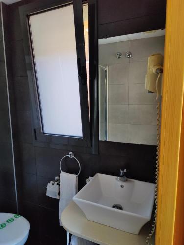 a bathroom with a white sink and a mirror at Hostal Manel in Pineda de Mar
