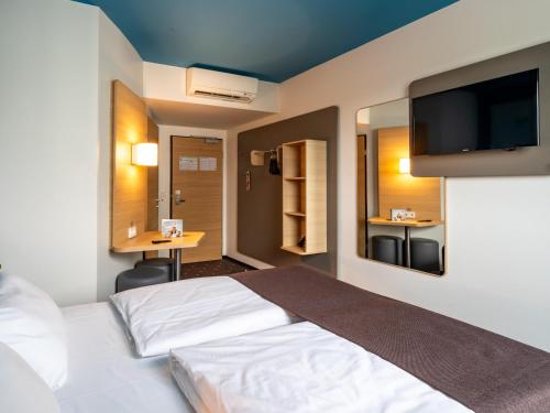 Habitación de hotel con cama y TV de pantalla plana. en B&B Hotel Wolfsburg-Weyhausen en Wolfsburg