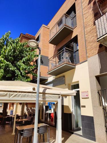 a street light in front of a building with tables and umbrellas at Hostal Manel in Pineda de Mar