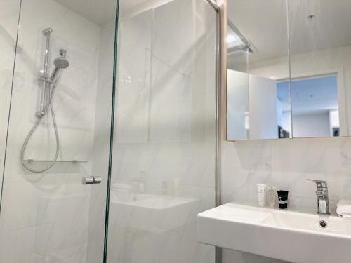 a white bathroom with a shower and a sink at Cultural Oasis Kingbed Apt at South Bank in Brisbane