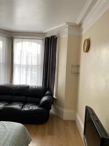 a living room with a black leather couch and a window at Crystal in Crystal Palace