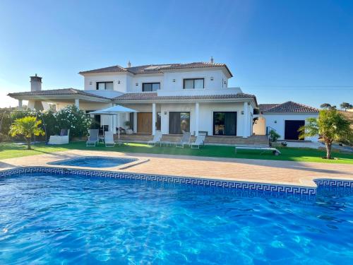 a villa with a swimming pool in front of a house at VILLA Casa Eden in Vila Nova De Cacela