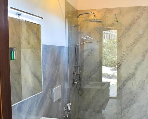 ein Bad mit einer Dusche, einem Waschbecken und einem Spiegel in der Unterkunft Giardini Malaspina in Bosa