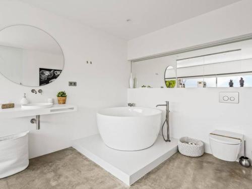 a white bathroom with a large tub and a sink at Design villa sea views and lap pool in Cabrils