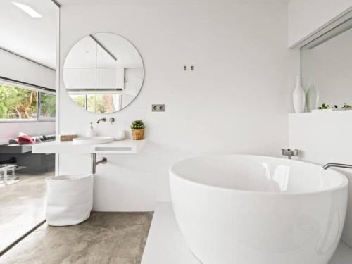 a white bathroom with a tub and a sink at Design villa sea views and lap pool in Cabrils