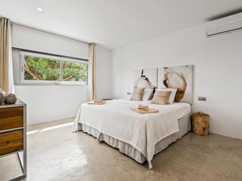 a white bedroom with a large bed and a window at Design villa sea views and lap pool in Cabrils