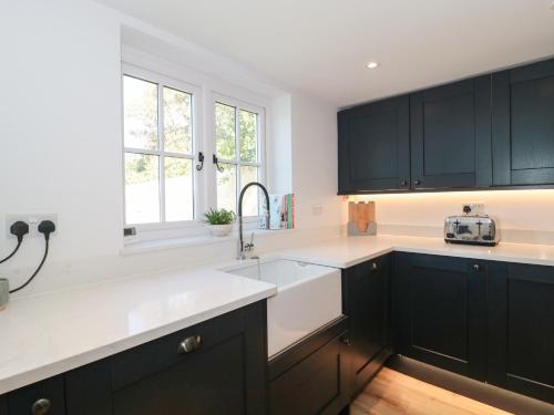 a kitchen with black cabinets and a sink at The Old Cottage in New Milton