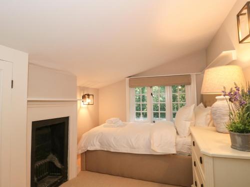 een slaapkamer met een bed en een open haard bij The Old Cottage in New Milton