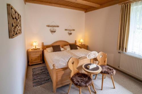 a bedroom with a bed with two chairs and a table at Landhaus Laih in Grafenau