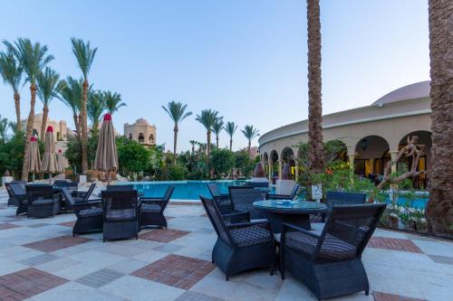 eine Terrasse mit Tischen und Stühlen neben einem Pool in der Unterkunft Makadi Palace - Couples and Families Only in Hurghada
