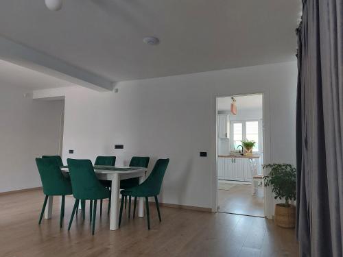 a dining room with a table and green chairs at Casa Abiiani in Oradea