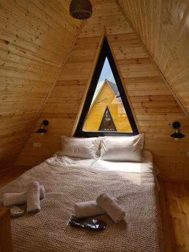 a bed in a wooden room with a window at Trip Zone Kazbegi in Kazbegi