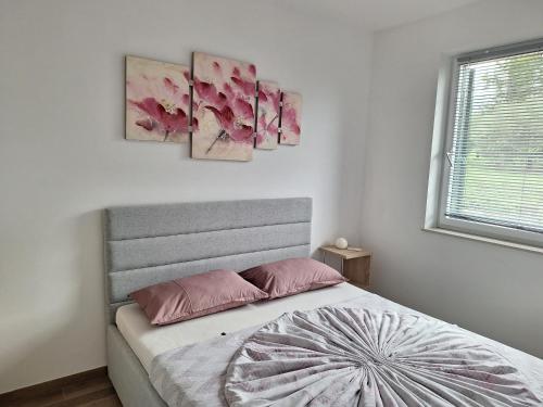 a bedroom with a bed with three paintings on the wall at Val&Sol Apartments in Sečovlje