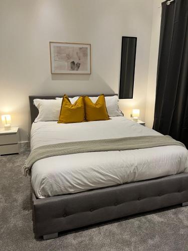 a bedroom with a large bed with yellow pillows at Modern 2bed Sutton in Sutton