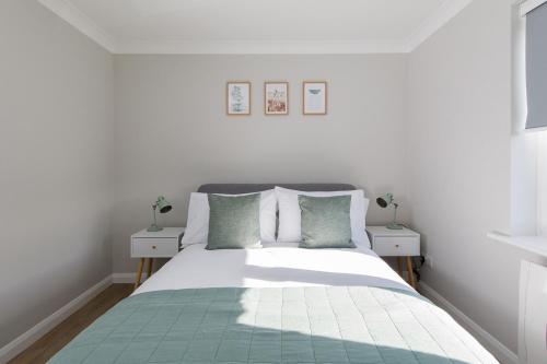 a white bedroom with a bed with green and white pillows at Little Blue in Chichester
