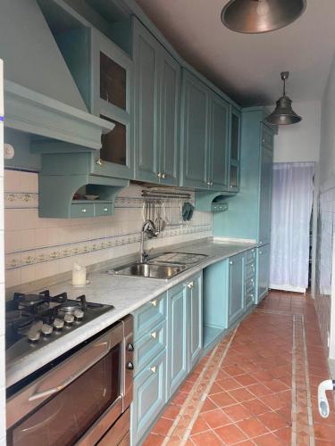 Benvenuto Beach House في مونتيروسّو ال ماري: مطبخ مع دواليب زرقاء ومغسلة