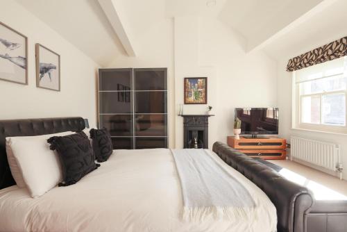 a bedroom with a bed with a couch and a television at Regency Stables in Brighton & Hove