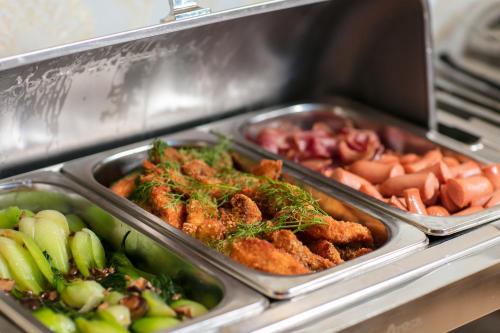 a buffet with three trays of food and vegetables at Sunland Halong Hotel and Restaurant in Ha Long