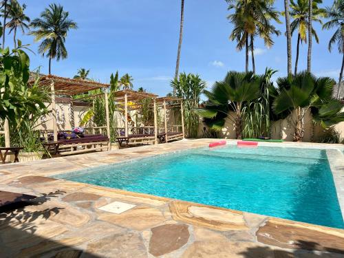 uma piscina num resort com palmeiras em Gadea Boutique Hotel& Gadea Garden Italian Restaurant em Jambiani