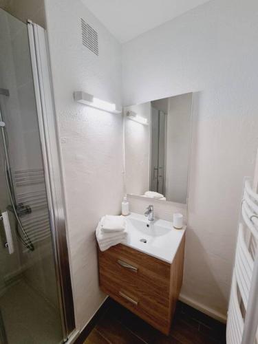 une salle de bain blanche avec un lavabo et une douche dans l'établissement studio avec vue sur mer, à Saint-Hilaire-de-Riez