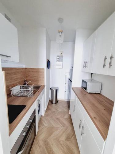 une cuisine avec des armoires blanches et des comptoirs en bois dans l'établissement studio avec vue sur mer, à Saint-Hilaire-de-Riez