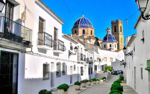 una calle de la ciudad con edificios blancos con cúpulas azules en Casa Lotus, en Altea